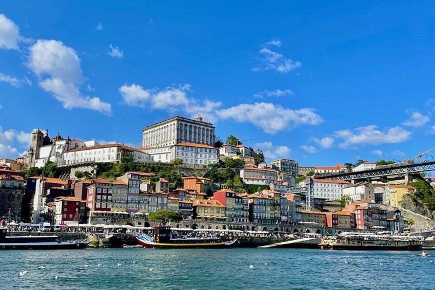 A coastal cityscape with historic buildings, a prominent white building, and a bridge. 2