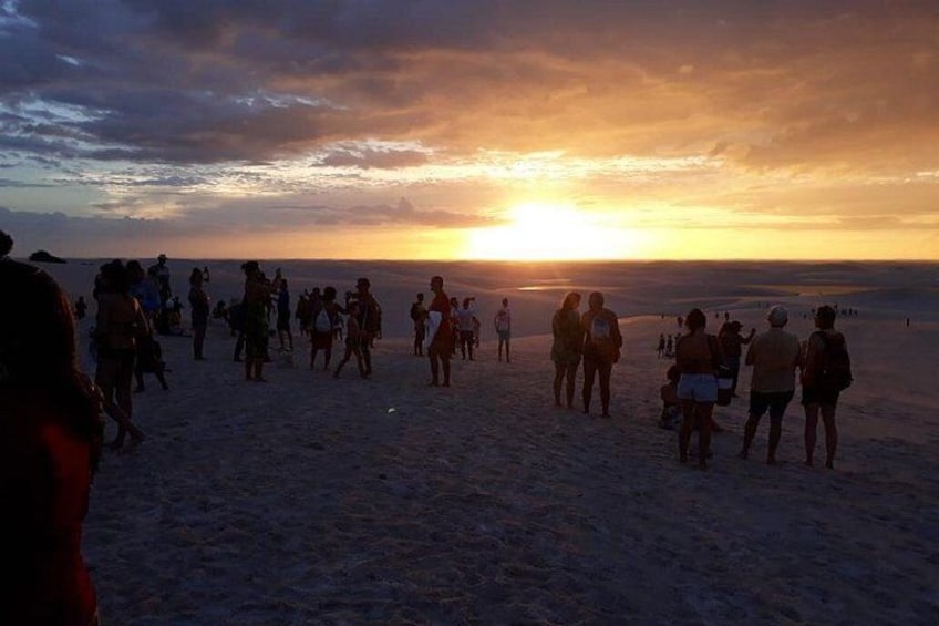 A group of people on a beach at sunset. 1