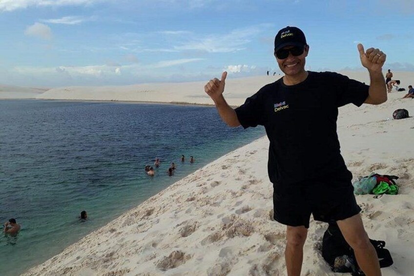 A person standing on a sandy beach with a clear blue sea in the background. 4