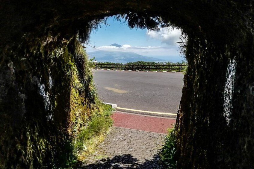 Vista a través de una obertura de cueva hacia un estacionamiento, con una carretera roja y un sendero pavimentado que se adentra en la cueva. 1