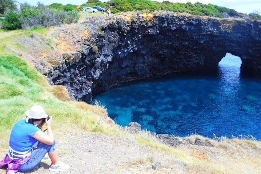 Una persona fotografiando una formación rocosa natural con una piscina azul cristalina. 2