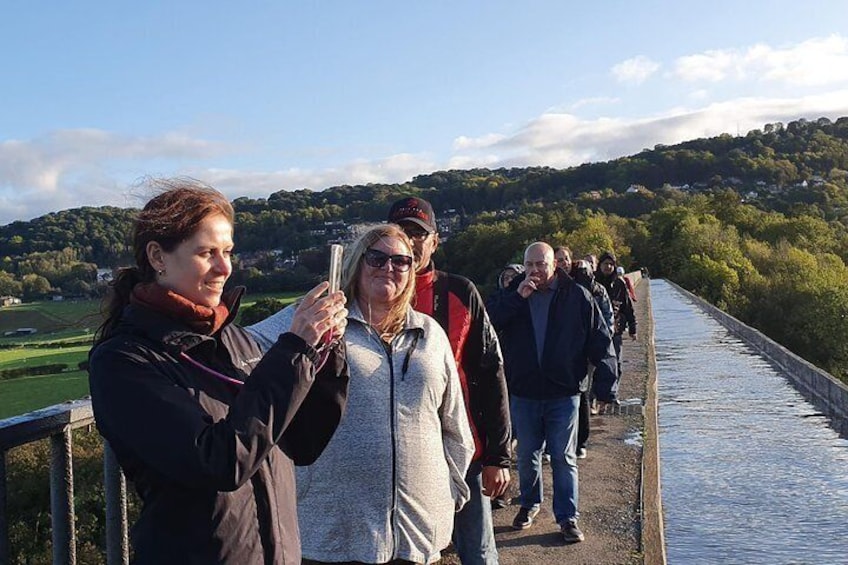 People walking on a bridge with a river and greenery in the background. 1