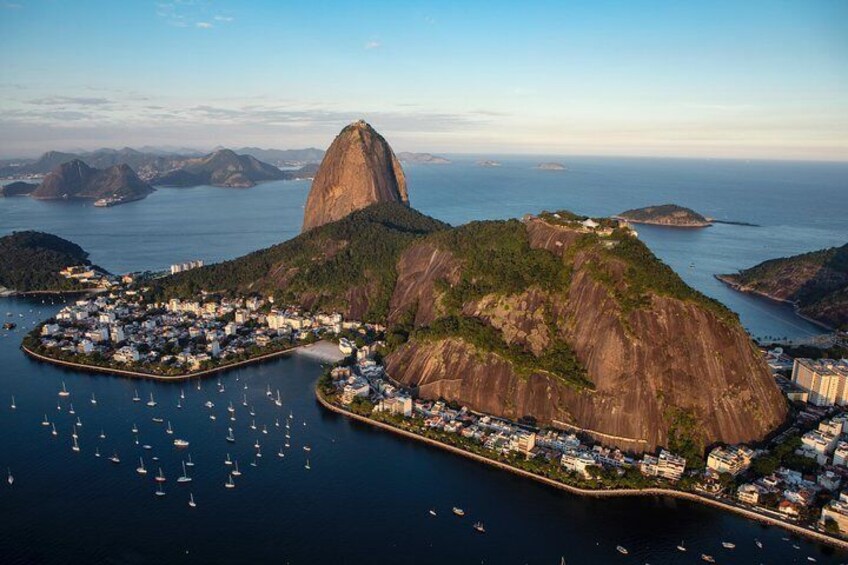 A coastal town with a prominent mountain, numerous boats, and a clear view of the ocean and distant islands. 5