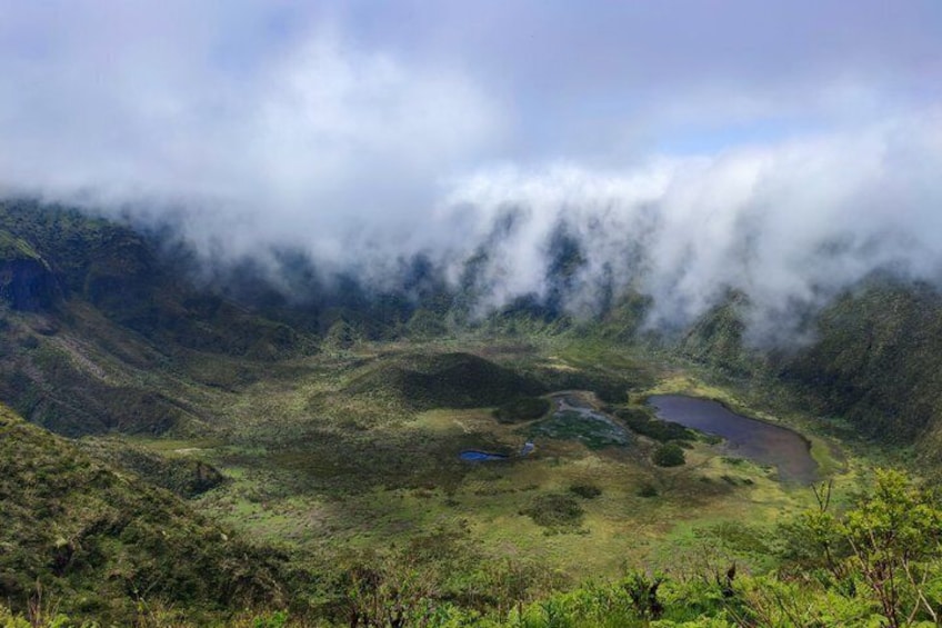 A mountainous landscape with a lake surrounded by greenery and clouds. 2