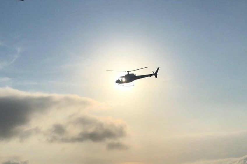Un helicóptero volando sobre las nubes, con el sol brillando a través de ellas. 1