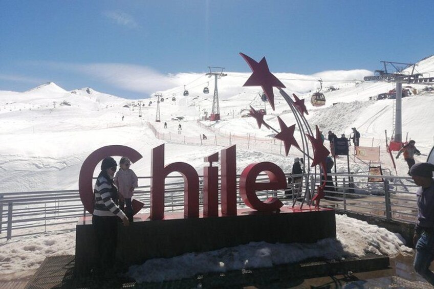 Ein großes Schild mit dem Schriftzug 'Chile', eine Seilbahn und eine verschneite Landschaft. 4