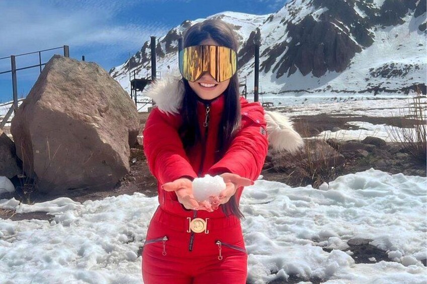 Eine Person in einem roten Schneeanzug mit einem fellbesetzten Kapuze, die einen Schneeball hält. 5