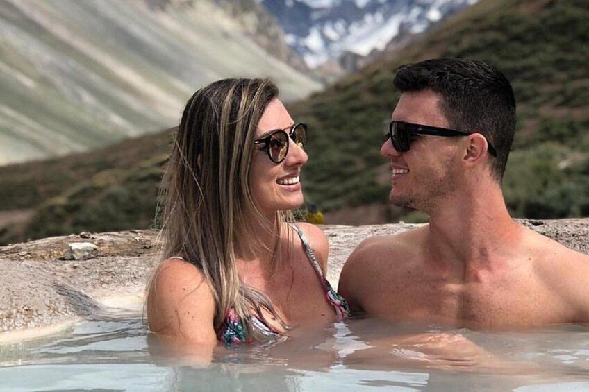Two people in a hot spring with a mountainous background. 2