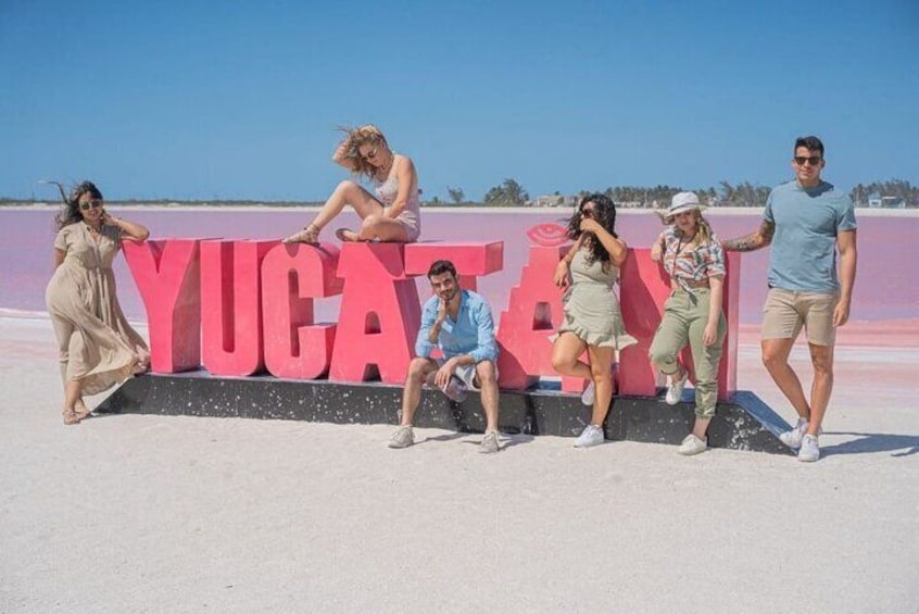 En gruppe mennesker poserer foran et stort skilt med 'Yucatan'. 3