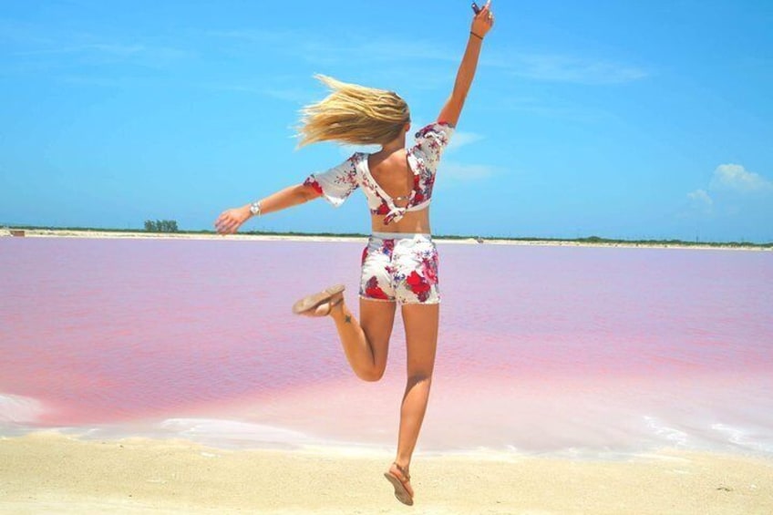 En person hopper på en strand med rosa vand. 1