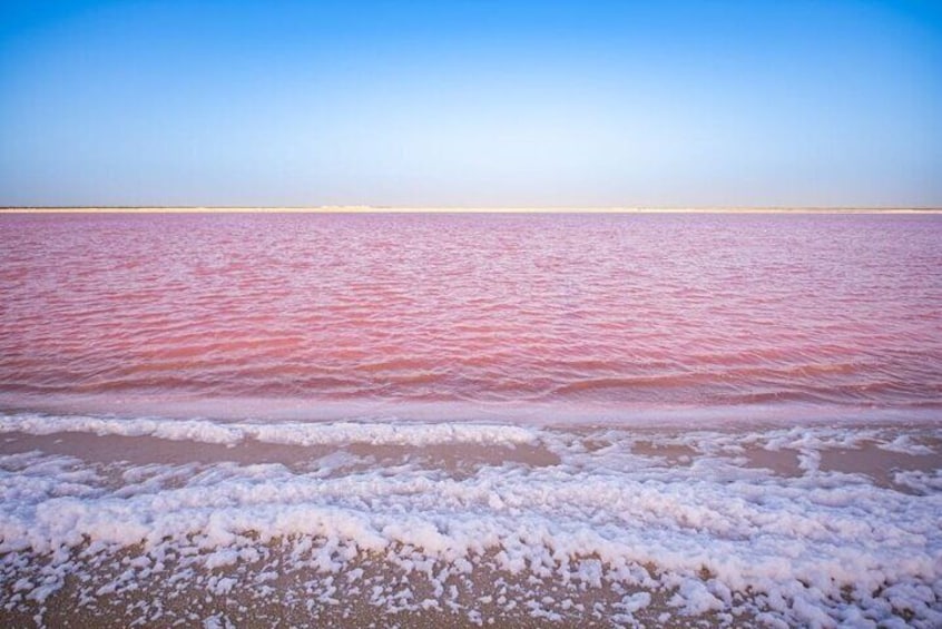 En strand med pink vand og hvidt skum langs kysten. 2