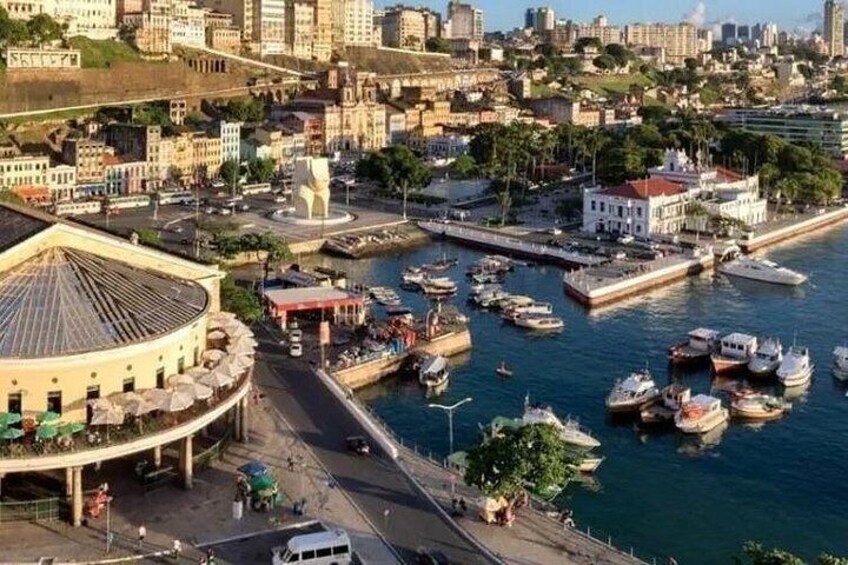 A coastal cityscape with a marina, historic buildings, and a prominent round structure. 2
