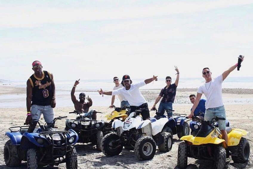 A group of people on a beach with ATVs. 1