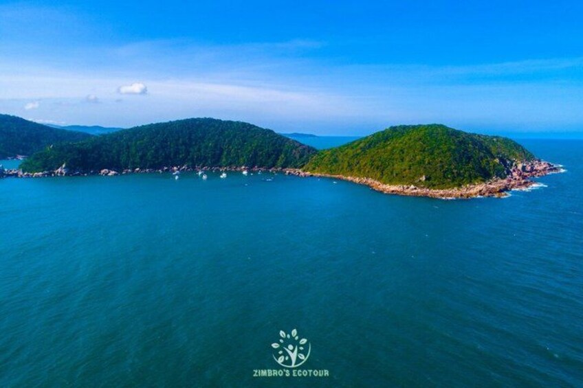 An aerial view of a coastal island with dense greenery and a clear blue sea. 4
