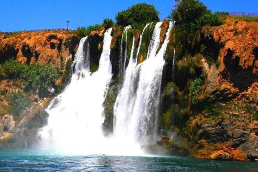 Une cascade à plusieurs niveaux se déversant dans un plan d’eau, le tout entouré d’un paysage rocheux et de végétation luxuriante. 2