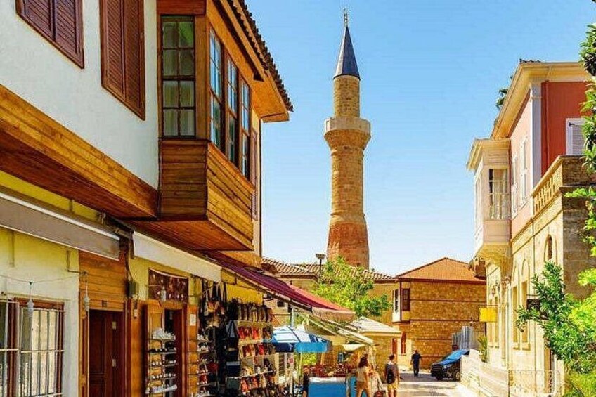 En gata med butiker, ett högt minarettorn och en klarblå himmel. 3