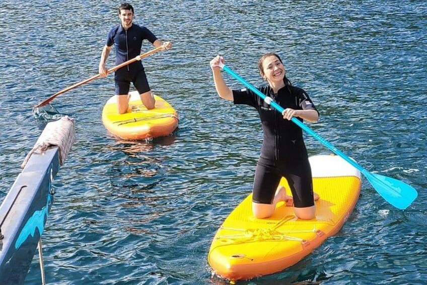 Two people paddleboarding on a calm body of water. 3