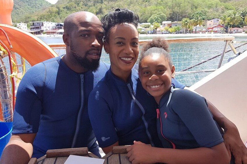 Three people in blue wetsuits on a boat with a pool and buildings in the background. 5
