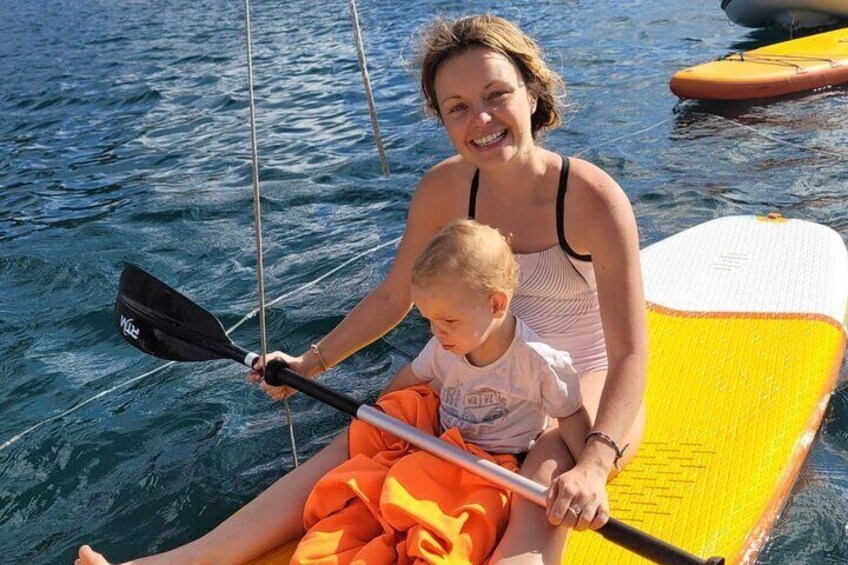 A woman and a child on a yellow paddleboard in the water. 4