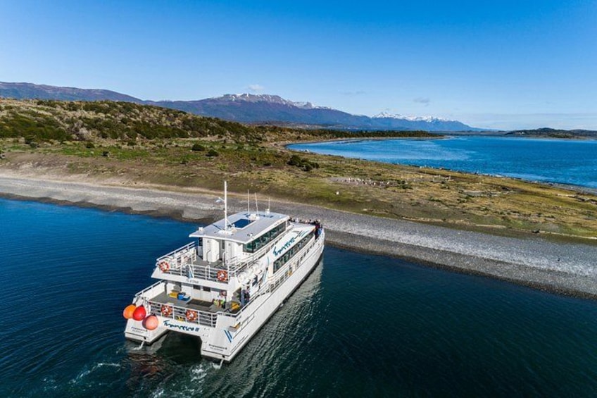 A white boat with a blue stripe on the water, a dock on the shore, and mountains in the background. 3