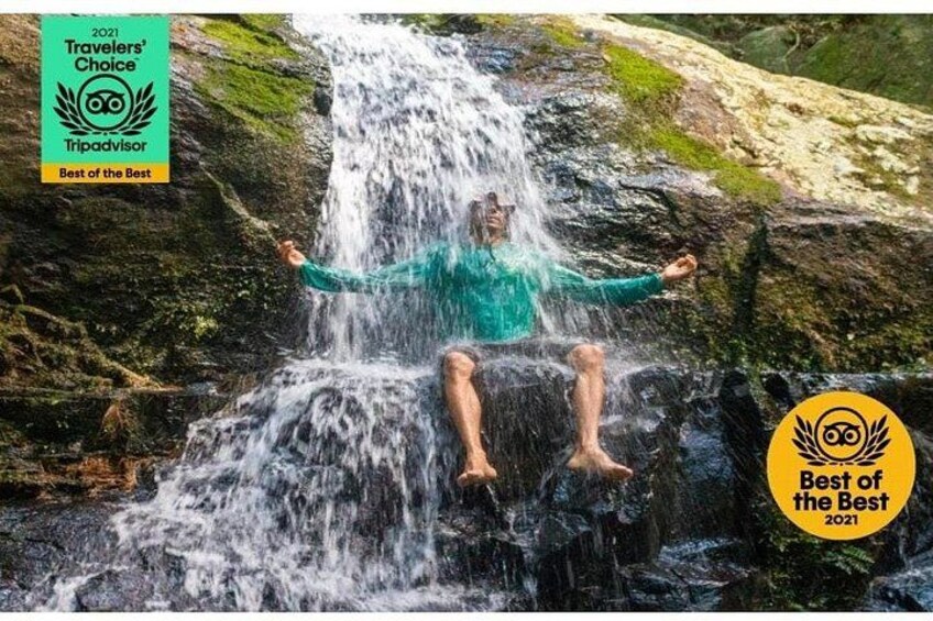 Una persona seduta su una roccia con le braccia aperte di fronte a una cascata. 2