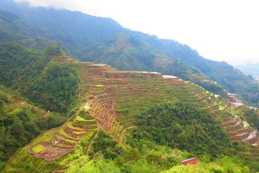 Terraced agricultural fields, a river, and dense forested hills. 1