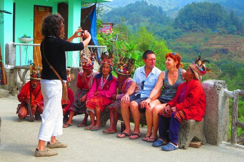 A group of people sitting on a ledge with a person taking a photo. 2
