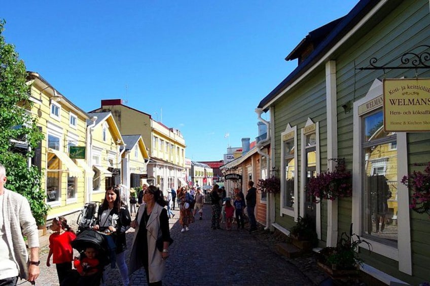 A cobblestone street lined with historic buildings, pedestrians, and flower boxes. 2