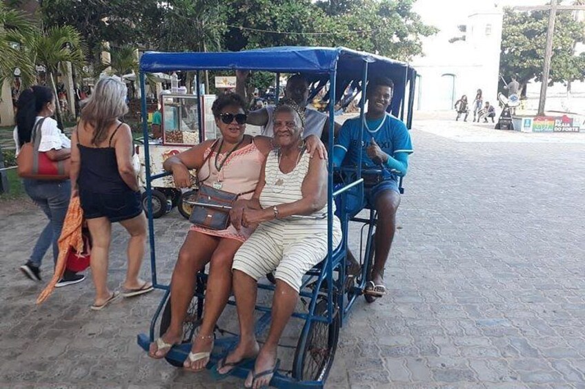 A group of people in a blue cart on a paved street. 4