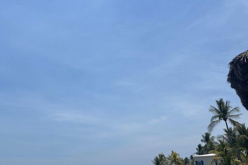 A clear sky with a few clouds, palm trees, and a building with a blue roof. 3