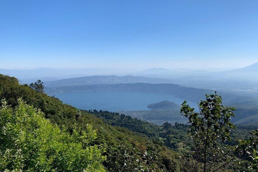 A mountainous landscape with a lake, dense greenery, and distant mountains. 5