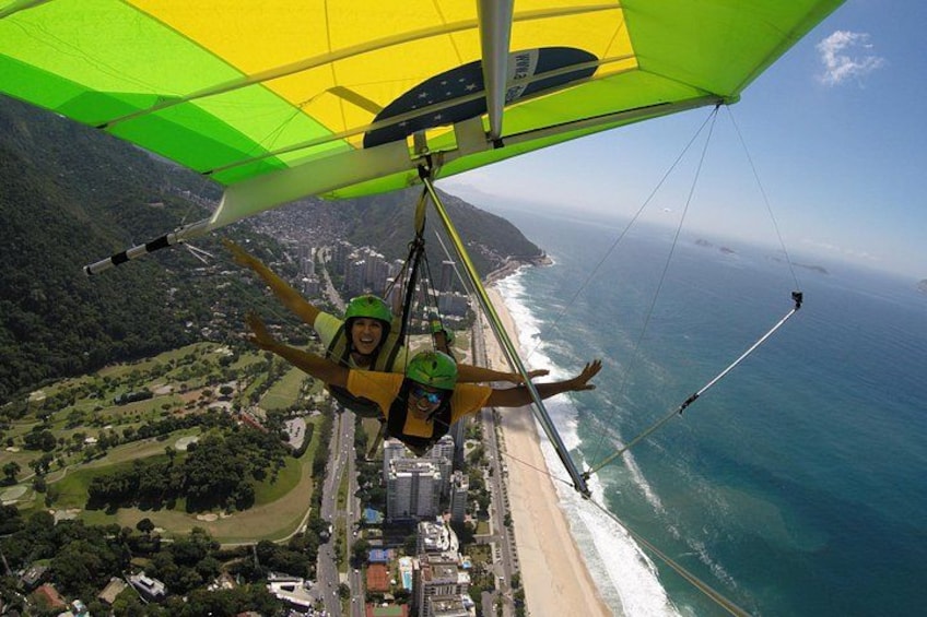 A paraglider flying over a coastal city with a beach and mountains in the background. 4