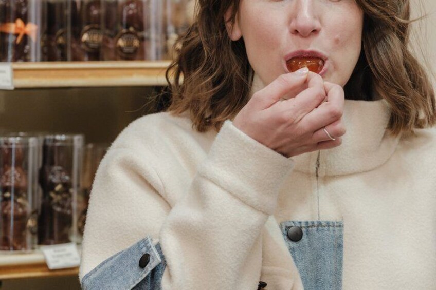 A person wearing a white sweater and denim overalls, holding a small object. 5