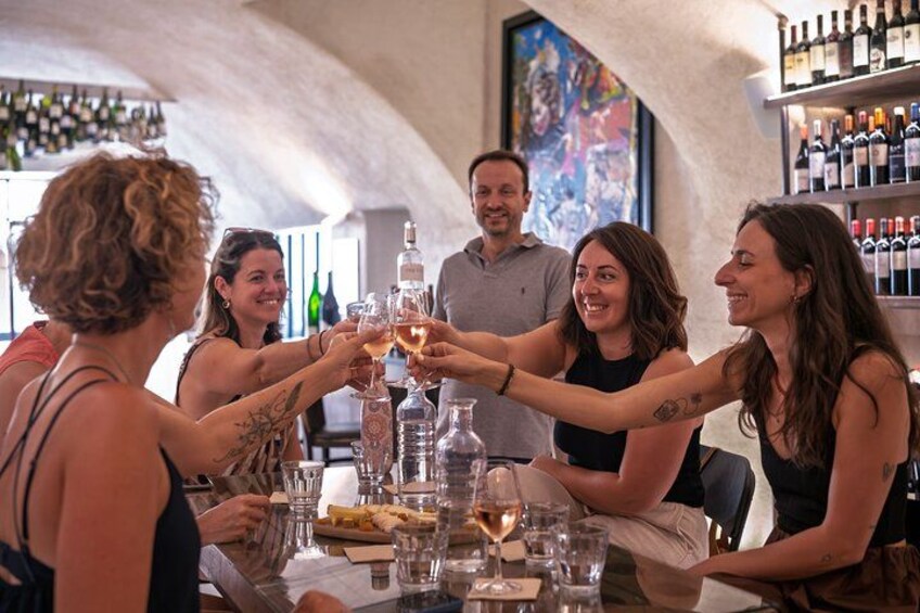 En grupp människor skålar med vinglas på en bar med inredning i sten. 1