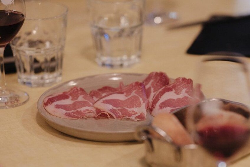 A plate of sliced meat, a glass of red wine, and a glass of water on a table. 5