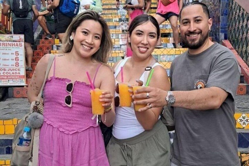 Three people holding drinks, a tiled wall, and a sign with prices. 3