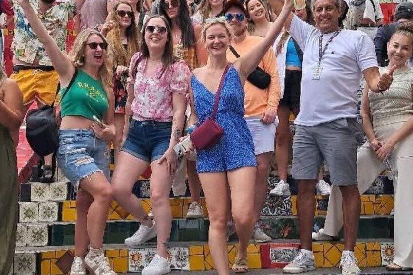 A group of people standing on steps with a tiled wall in the background. 4