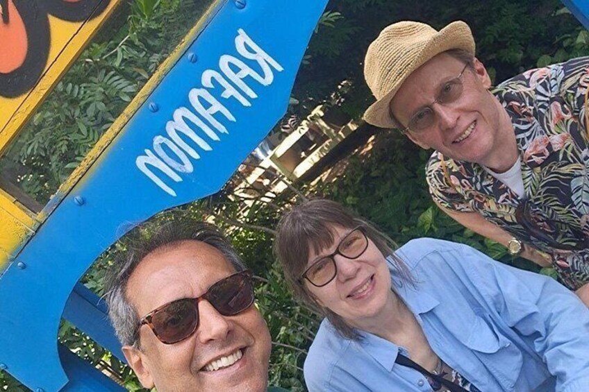 Three people standing in front of a blue structure with the word 'PARK' visible. 2