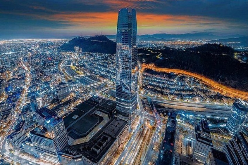 Une vue d’une ville au crépuscule, avec un gratte-ciel imposant, des rues illuminées et des bâtiments environnants. 2