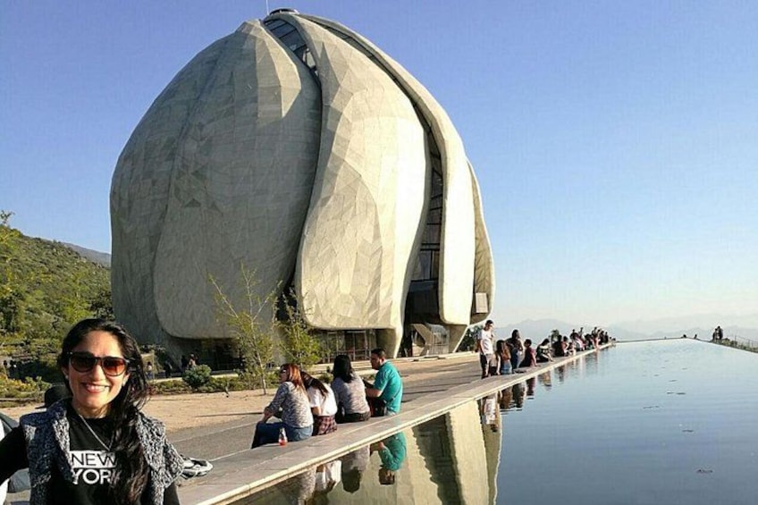 Un grand bâtiment à l’architecture originale, doté d’une façade incurvée, entouré d’une étendue d’eau paisible et d’un groupe de personnes se trouvant sur une plateforme d’observation. 1