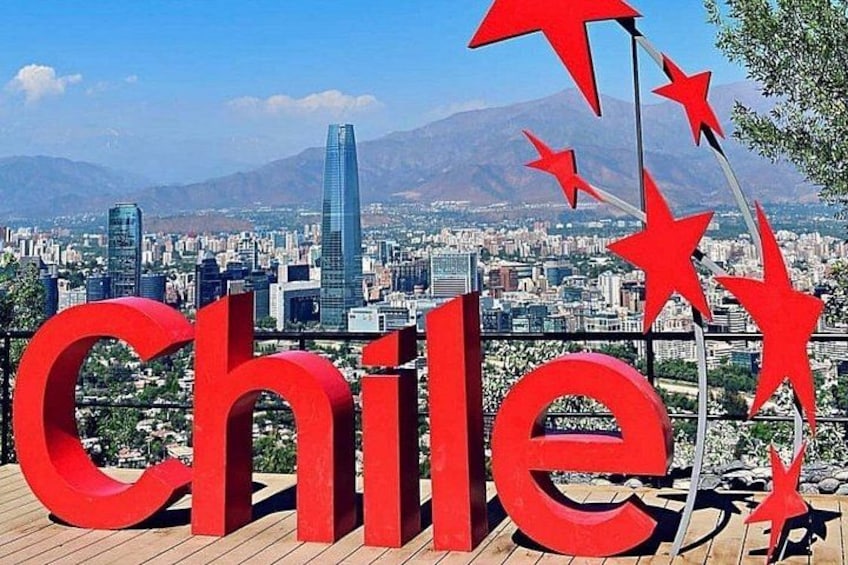 Un grand panneau rouge sur lequel on peut lire le mot « Chili », orné d’étoiles, se dresse sur un paysage urbain avec des montagnes en arrière-plan. 5