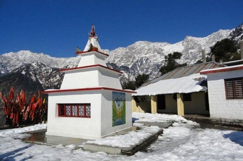 Un paisaje montañoso cubierto de nieve con un edificio blanco con tejado rojo y un pequeño santuario. 2