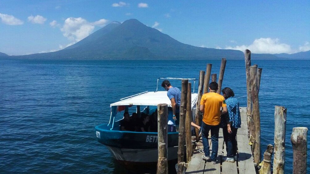 A boat docked at a wooden pier with a mountain in the background. 5
