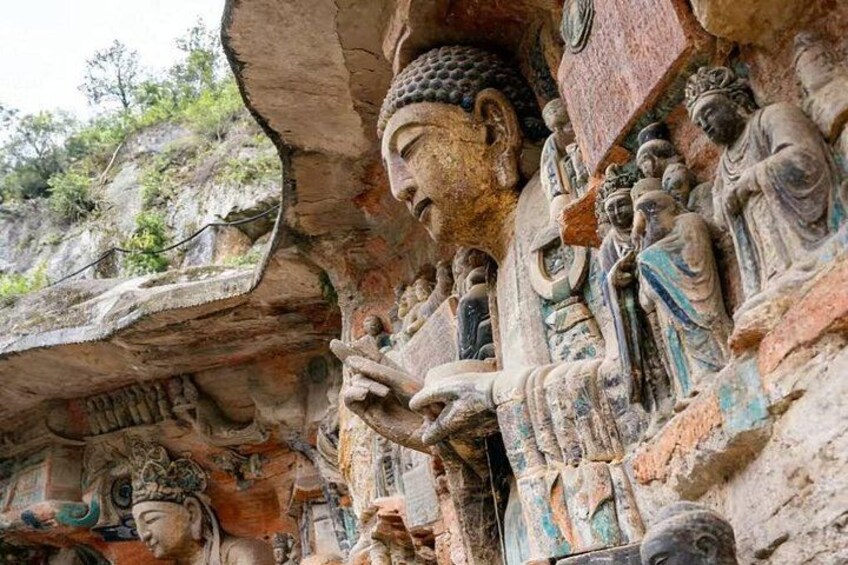 A large Buddha statue with smaller figures, carved into a cliffside. 2