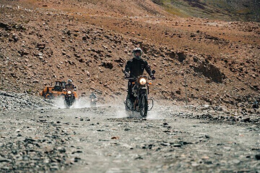 A person on a motorcycle and a tractor on a rocky terrain. 2