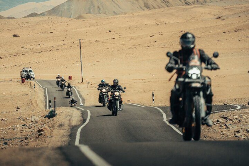 A group of motorcyclists on a winding road in a desert landscape. 1