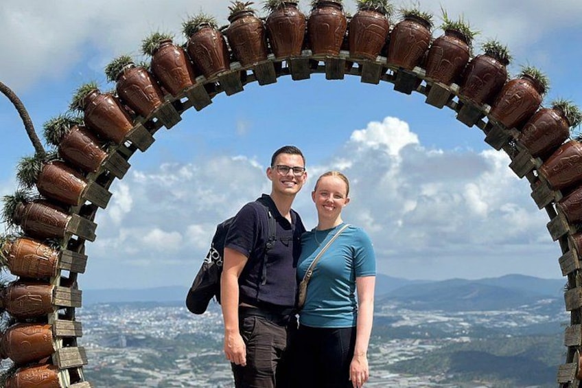 A couple standing in front of a wooden archway decorated with ceramic pots. 4