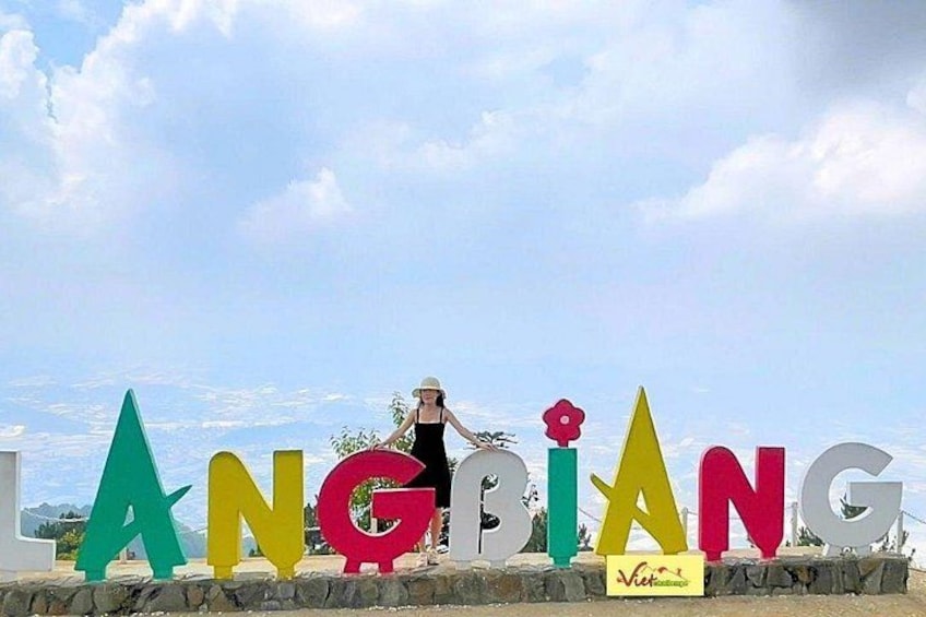 A person standing in front of colorful letters spelling 'ANGPIANG' with a mountainous landscape in the background. 3
