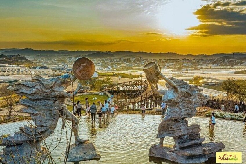 Una escultura que muestra una figura cargando un balde, un puente y una masa de agua. 4