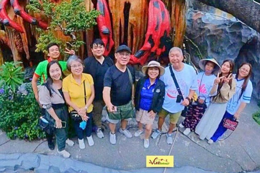 A group of people posing in front of a rock formation with red and black patterns. 5